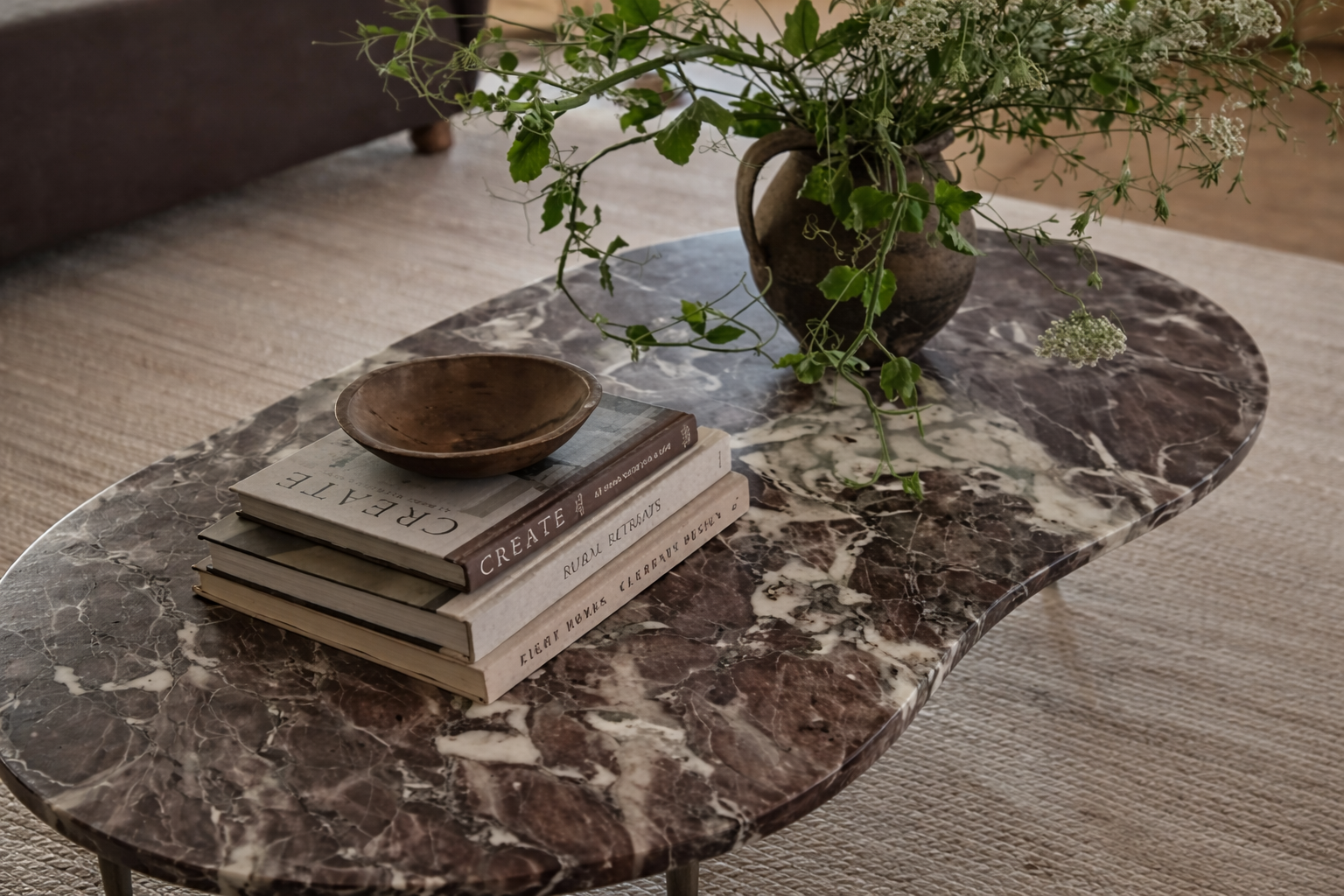 Marble coffee table with books and a vase of flowers in a living room setting